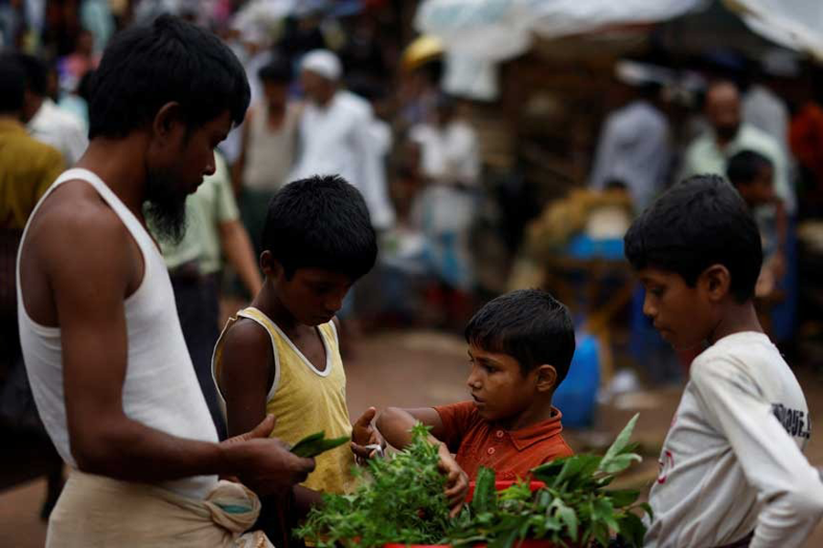 A Rohingya refugee child sells vegetables on the street, along a kitchen market inside a refugee camp, in Cox's Bazar, Bangladesh, Aug 27, 2025.