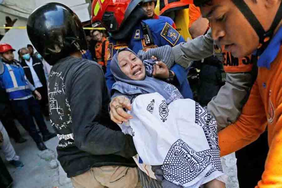 Members of the search and rescue operations carry a relative of the victim of a collapsed building, after a hall collapsed while students were praying at the Al-Khoziny Islamic boarding school on Monday, in Sidoarjo, East Java province, Indonesia, Oct 1, 2025.