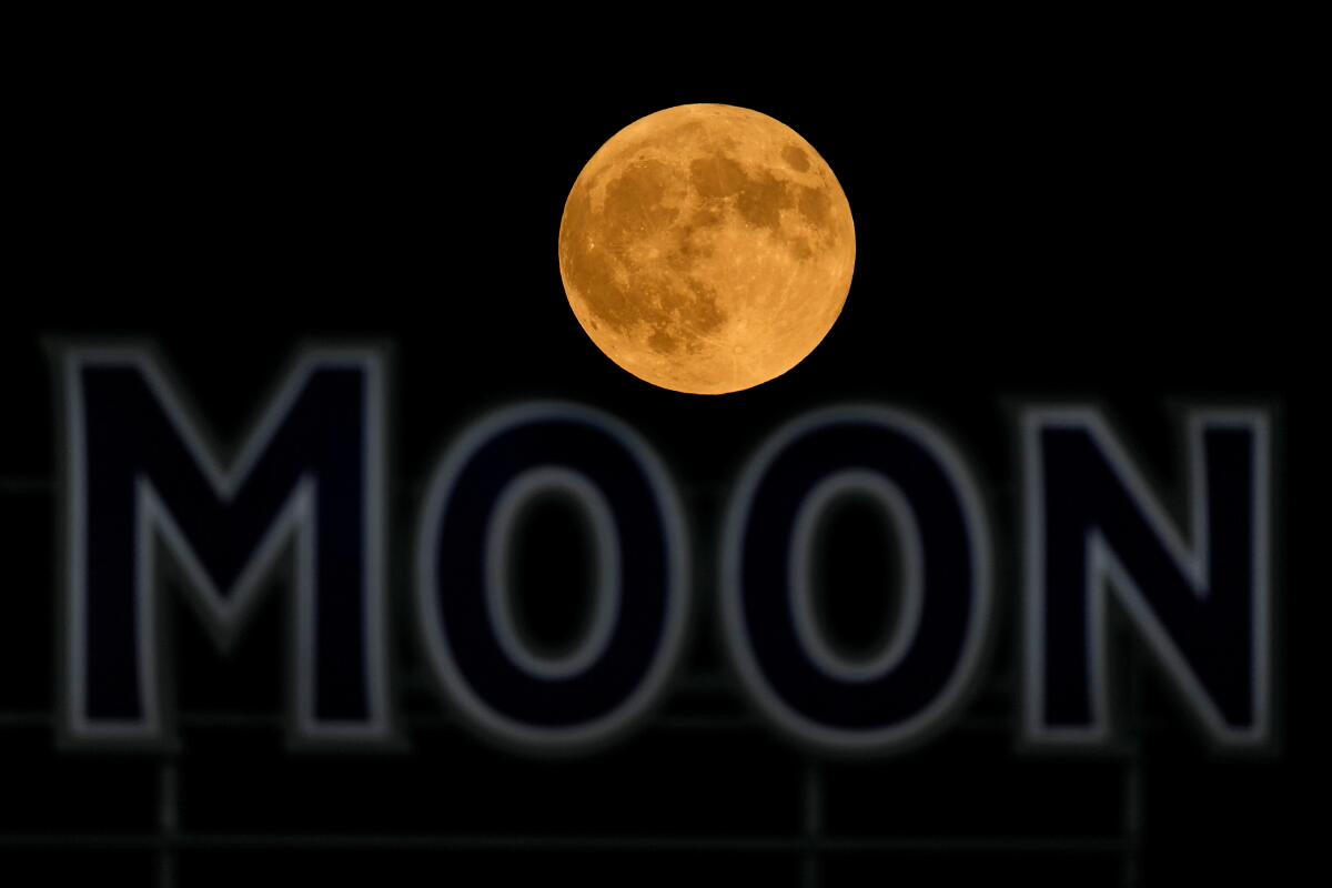FILE - The full moon rises in the over a beer sign in the outfield at Kauffman Stadium during a baseball game between the Kansas City Royals and the Detroit Tigers, Tuesday, Sept. 17, 2024, in Kansas City, Mo. (AP Photo/Charlie Riedel, File)