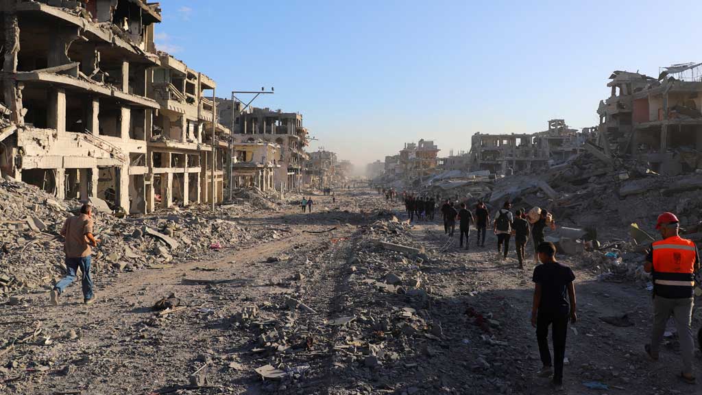 Palestinians walk through a damaged neighbourhood in the aftermath of an Israeli operation, after Israel's government ratified a ceasefire with Hamas, in Gaza City Oct 10, 2025. REUTERS/ Ebrahim Hajjaj