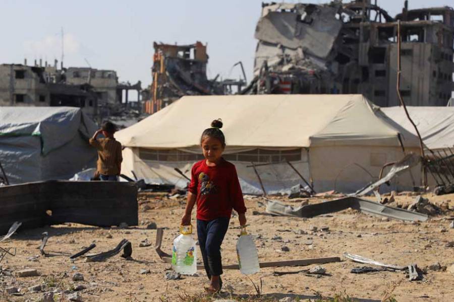 A displaced Palestinian girl carries water containers near tents, amid a ceasefire between Israel and Hamas, in Gaza City, Oct 19, 2025.