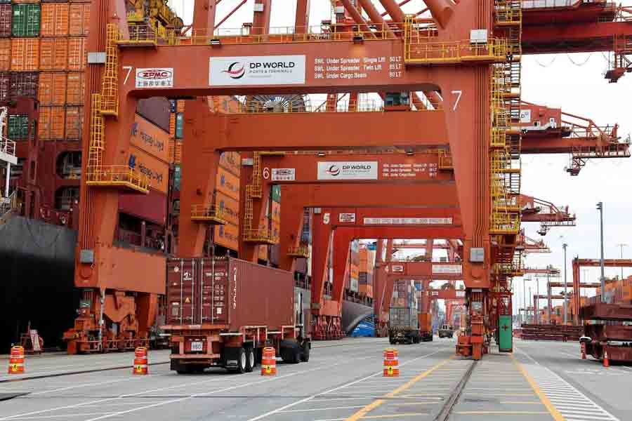 A truck carries a container near a cargo ship bound for Japan at the Centerm container ship terminal at the Port of Vancouver in Vancouver, British Columbia, Canada August 3, 2025.