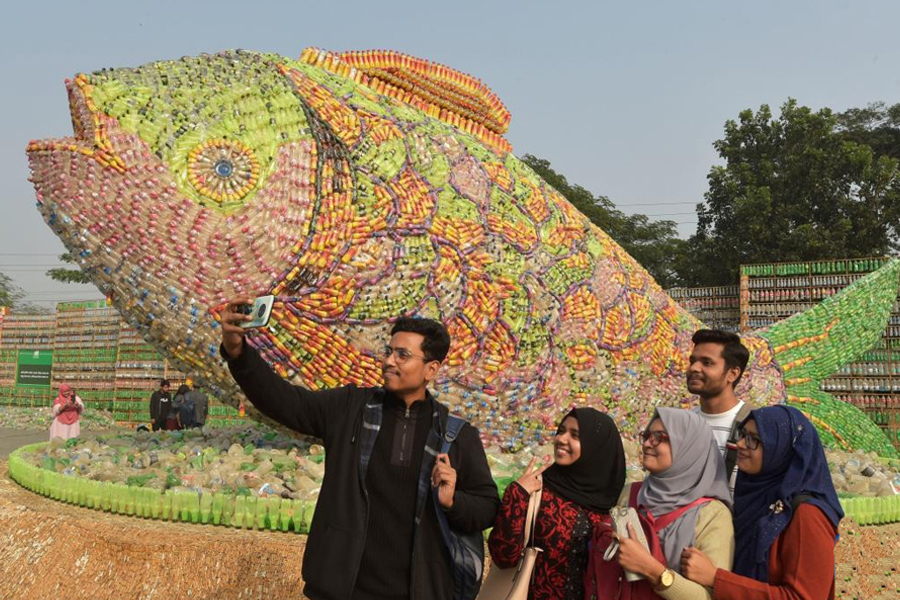 Young people take selfies in front of a fish-shaped installation made of empty plastic bottles and cigarette filters at an exhibition in Bangladeshi capital Dhaka, Jan. 5, 2023. The dividend of youth in Bangladesh is not merely economic. it is moral and civic also —Xinhua Photo