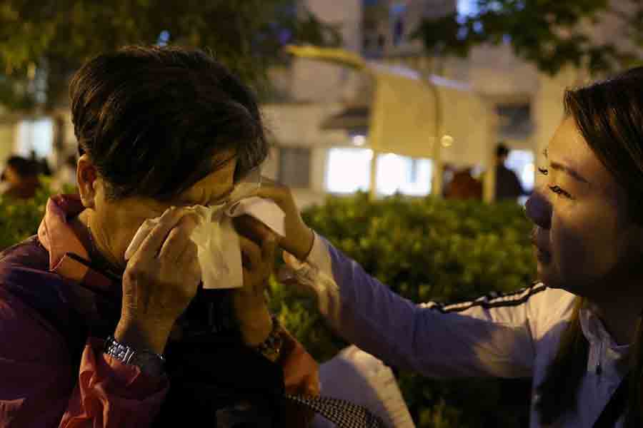 Michelle Liu, a social worker and counsellor, helps Cheung Yuk-ling, 73, who survived the deadly fire at the Wang Fuk Court housing complex, wipe her tears in Hong Kong, China, November 28, 2025.