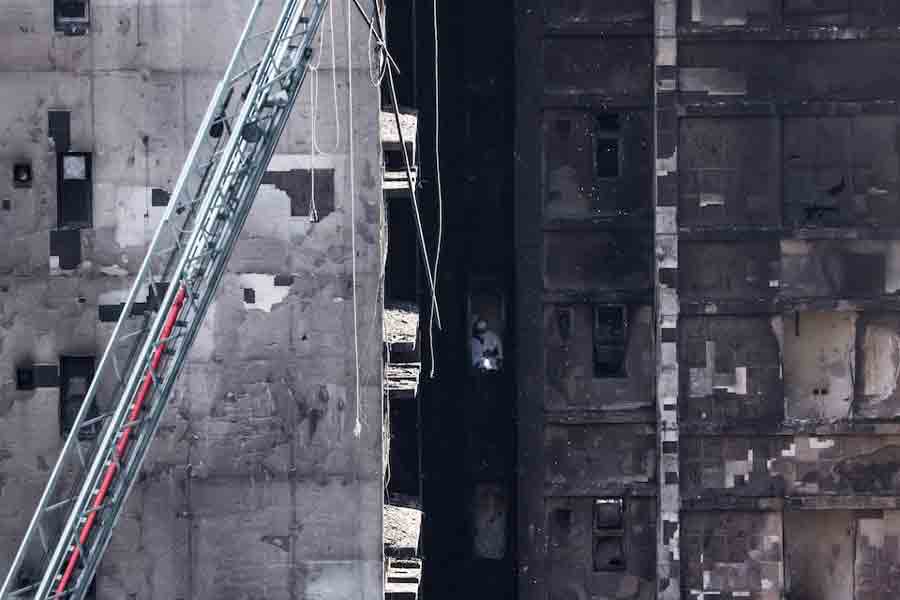 A man wearing personal protective equipment inspects inside one of the buildings of the Wang Fuk Court housing complex after the deadly fire, in Tai Po, Hong Kong, China, November 29, 2025.