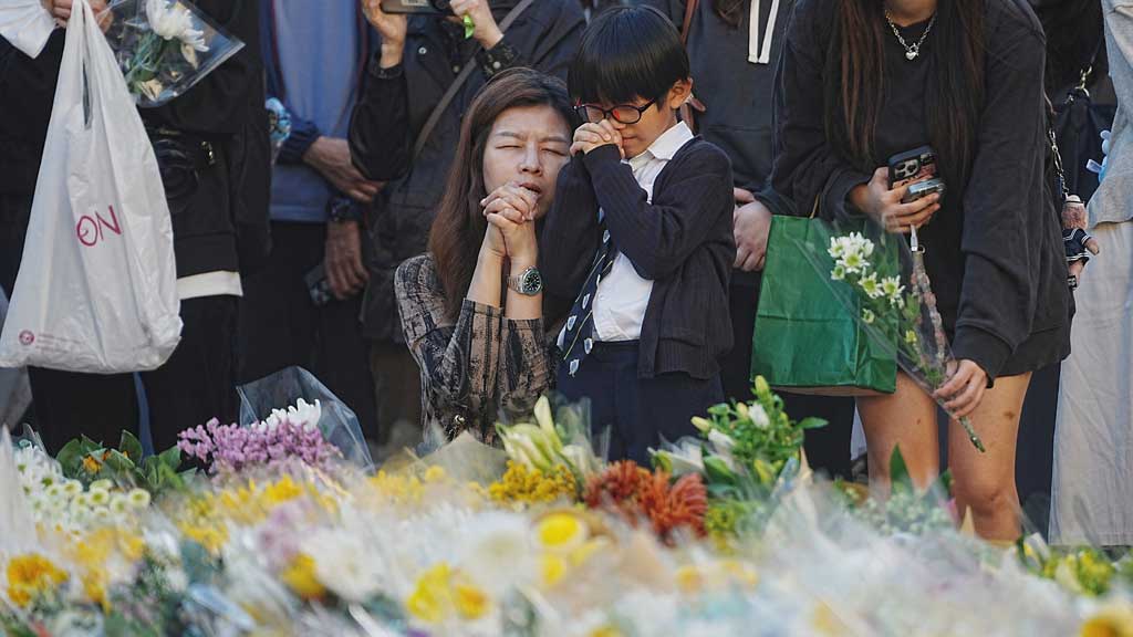 People pray as they lay flowers at a makeshift memorial near Wang Fuk Court housing estate to pay tribute to victims of the deadly fire at the housing complex, in Tai Po, Hong Kong, China, Dec 1, 2025. REUTERS/Lam Yik
