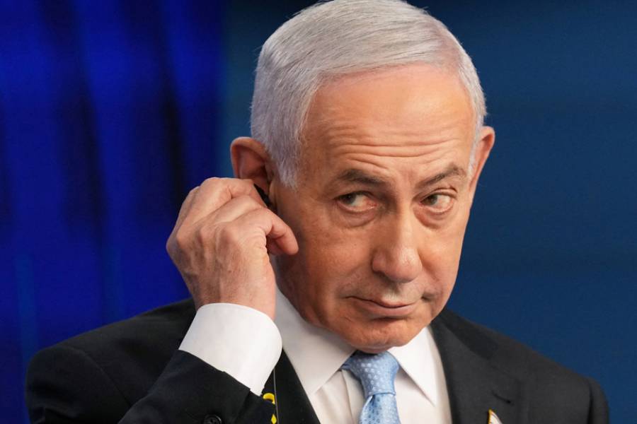 Israeli Prime Minister Benjamin Netanyahu adjusts the headphones during a joint press conference with German Chancellor Friedrich Merz (not pictured) in Jerusalem Sunday, Dec. 7, 2025.