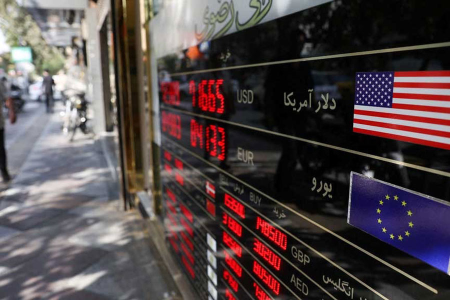 People walk past a sign at a currency exchange as the value of the Iranian Rial drops, in Tehran, Iran, Oct 5, 2025.