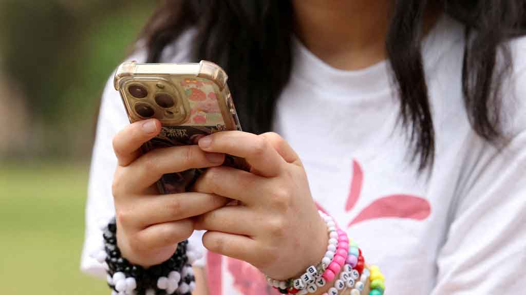 A girl poses holding her phone after an interview discussing Australia's social media ban for users under 16, which is scheduled to take effect on Dec 10, in Sydney, Australia, Nov 22, 2025. REUTERS