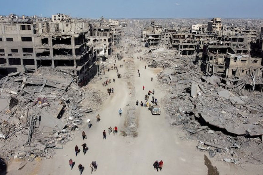 A drone view shows Palestinians walking past the rubble, following Israeli forces' withdrawal from the area, amid a ceasefire between Israel and Hamas in Gaza, in Gaza City, October 11, 2025.