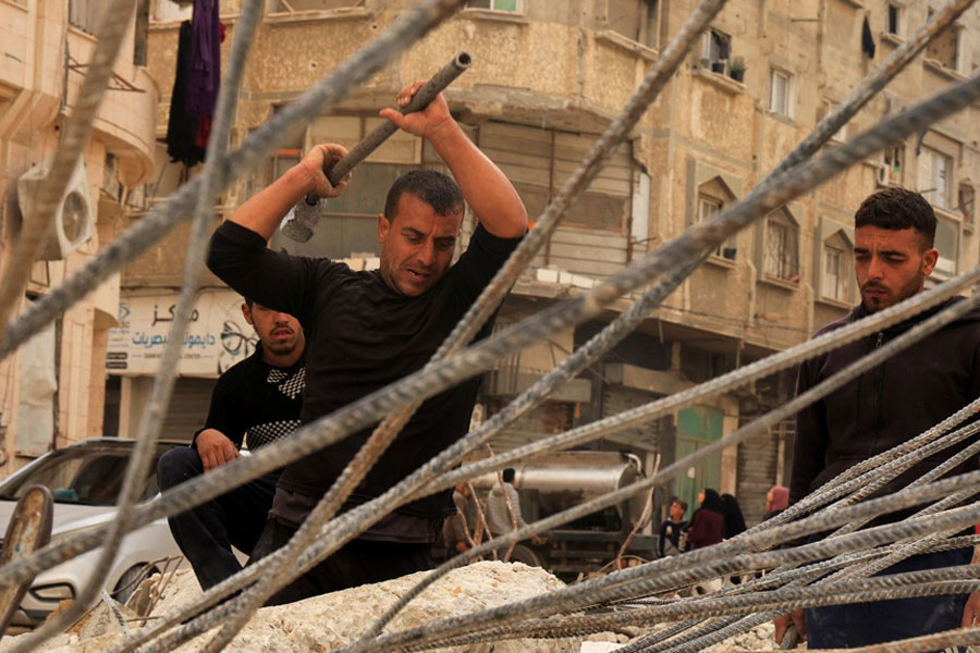 Palestinian workers break concrete to extract steel bars from destroyed homes, relying only on simple hand tools amid a severe shortage of construction materials caused by long-standing restrictions on the entry of cement and iron, in Khan Younis in the southern Gaza Strip, Dec 9, 2025.