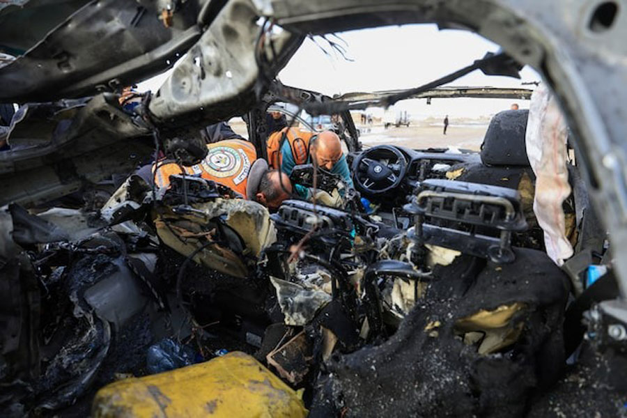 Palestinians inspect the site of an Israeli strike on a car in Gaza City, December 13, 2025.