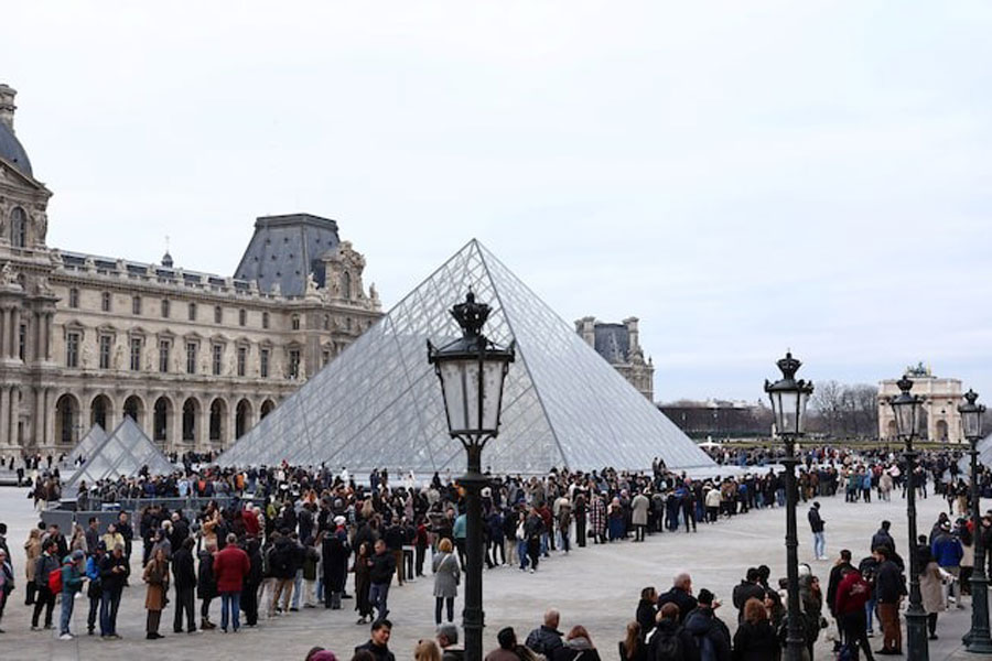 People queue near the glass Pyramid of the Louvre Museum to enter the museum which remains closed as its staff continue discussions on whether to extend a strike over pay and working conditions at the museum, the state of the museum's buildings and staffing issues, two months after a spectacular heist which saw thieves make off with jewels in broad daylight, in Paris, France, December 17, 2025.