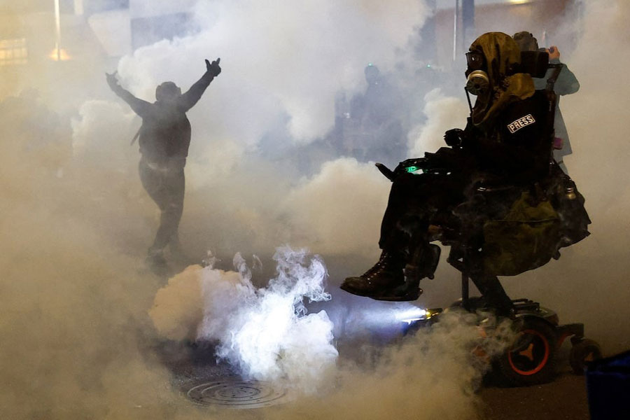 A person gestures amid tear gas as law enforcement officers advance to disperse demonstrators near US Immigration and Customs Enforcement (ICE) headquarters in Portland, Oregon, US, October 4, 2025.