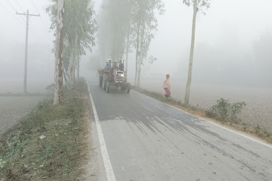 Dense fog largely reduces visibility, forcing vehicles to move on a road with their headlights on in Gaibandha district town — FE photo