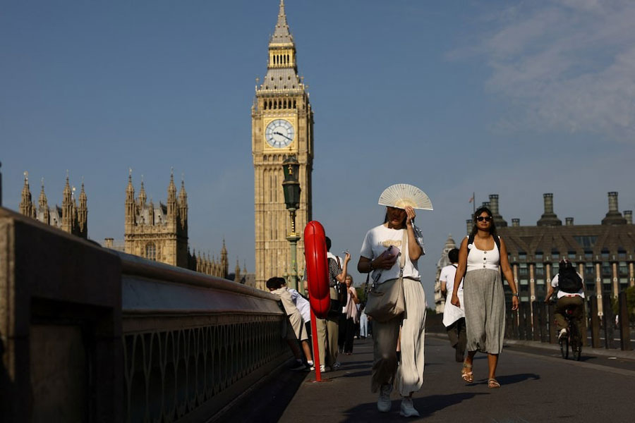 Women shelter from the sun under an umbrella at Green Park during a hot and sunny day, in London, Britain, August 15, 2025.