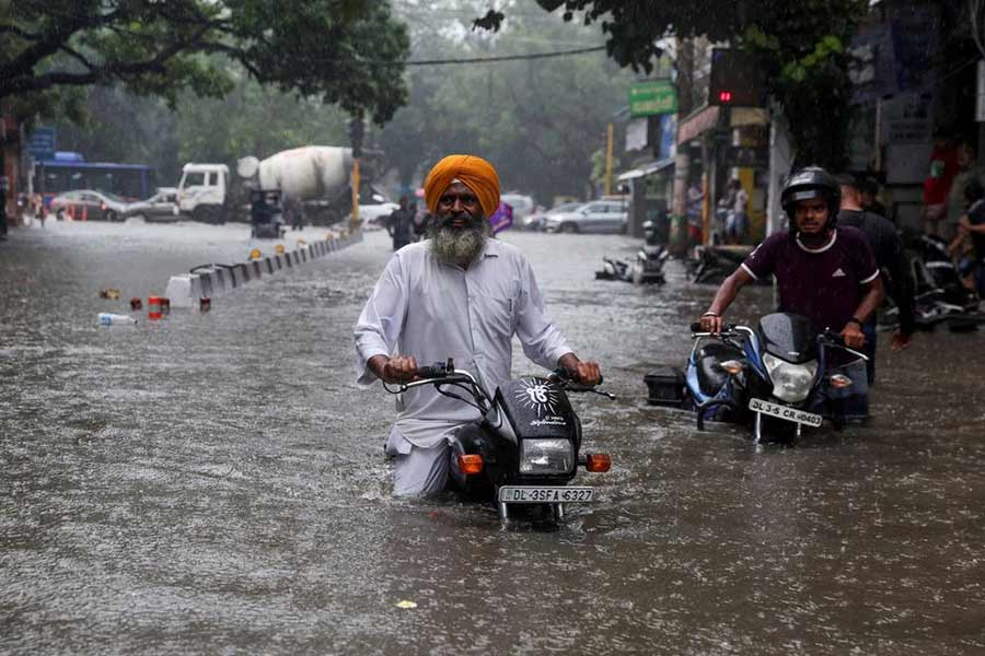 A man on his motorbike wading through a flooded street after heavy rains in New Delhi on Saturday –Reuters photo