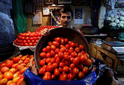 A vendor loads tomatoes in a bag for a customer at a wholesale vegetable market in Mumbai, India, Mar 14, 2018.