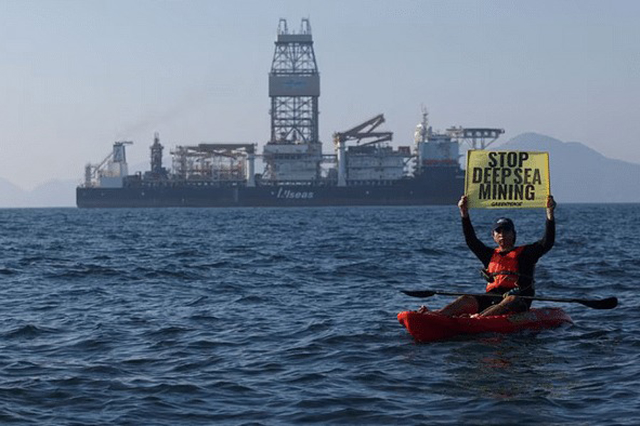 A Greenpeace activist holds a sign as he confronts the deep sea mining vessel Hidden Gem, commissioned by Canadian miner The Metals Company, as it returned to port from eight weeks of test mining in the Clarion-Clipperton Zone between Mexico and Hawaii, off the coast of Manzanillo, Mexico Nov 16, 2022.