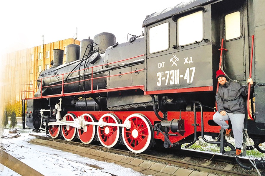 George poses for a photo with a steam locomotive at Murmansk Railway Station in Russia — Collected