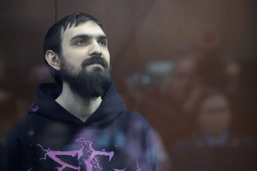 Russian comedian Artemy Ostanin stands behind a glass wall in an enclosure for defendants during a court hearing after his March 2025 arrest over a stand up performance, in Moscow, Russia, February 4, 2026.