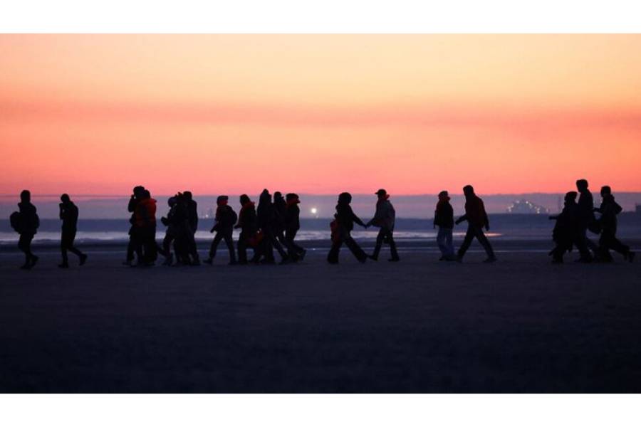 Migrants walk along the beach before trying to board an inflatable dinghy leaving the coast of northern France in an attempt to cross the English Channel to reach Britain, from the beach of Petit-Fort-Philippe in Gravelines, near Calais, France, Sept 27, 2025.