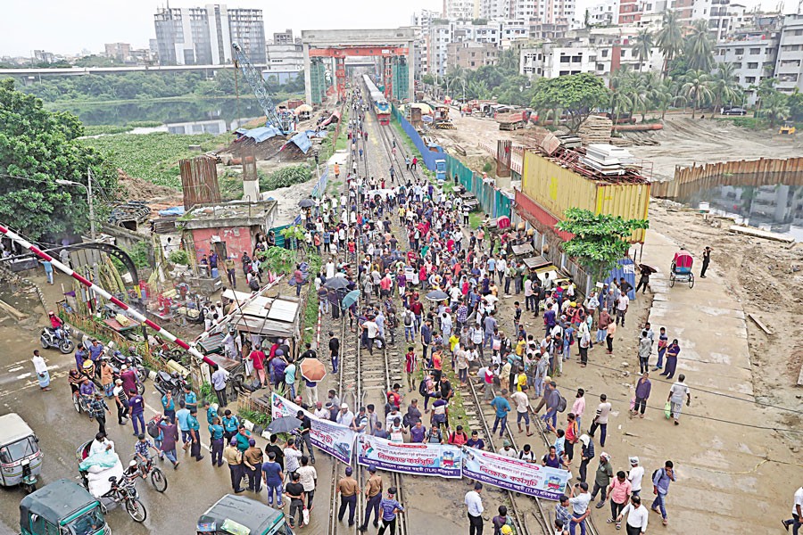 Railway workers stage a demonstration on the rail tracks close to the FDC Gate in Tejgaon area of the city on Sunday, blocking the train movement for about five hours, to press their demand that their jobs be made permanent. — FE photo