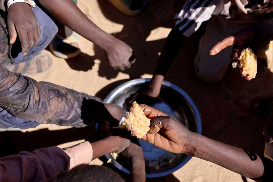 Orphaned Sudanese refugee children from al-Fashir share a free meal of pasta and meat provided by the "Group Kitchen Project," led by Najwa Isa Adam, inside the Tine transit camp in eastern Chad, as they flee ongoing clashes between the paramilitary Rapid Support Forces (RSF) and the Sudanese army, Nov22, 2025. REUTERS/Amr Abdallah Dalsh
