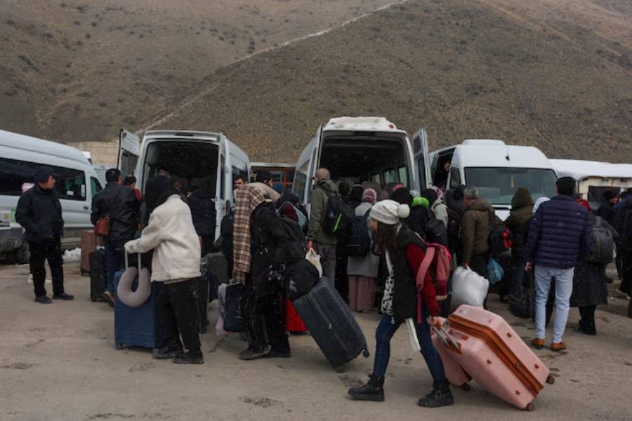 People wait for transportation to the city center after crossing from Iran into Turkey at the Kapikoy Border Gate in eastern Van province, Turkey, March 2, 2026.