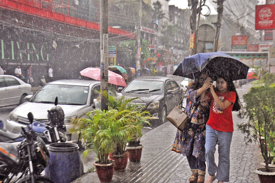 Two pedestrians crossing the capital's Bailey Road area amid a spell of rainfall on Monday. — FE Photo