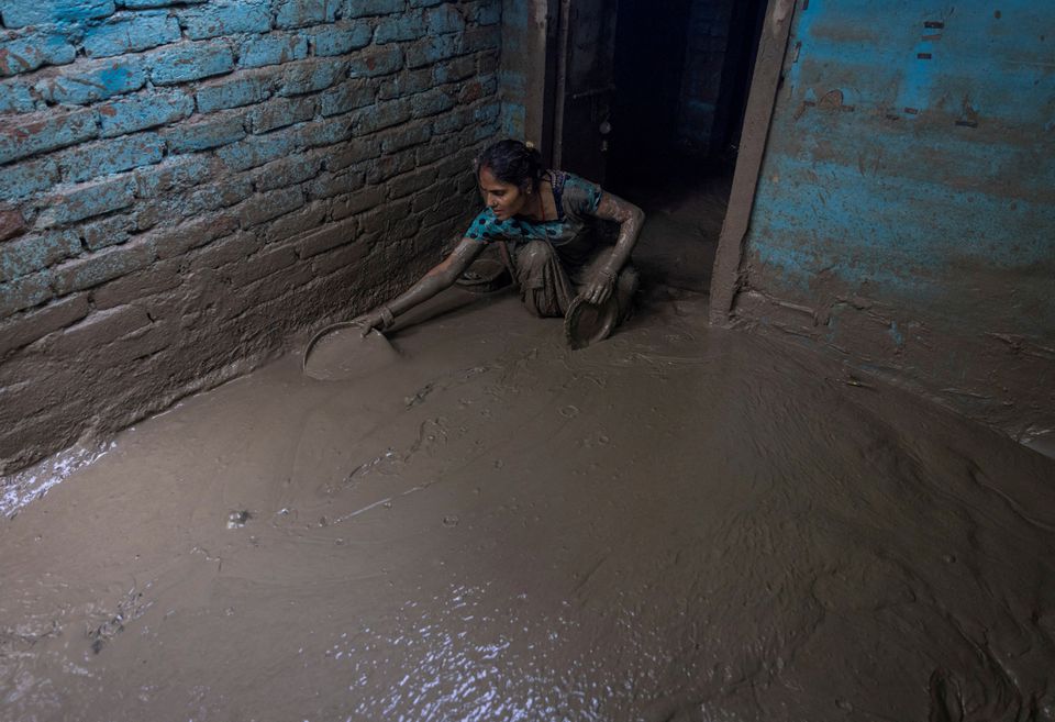 Munni Devi, 28, cleans the mud from the entrance of her house as flood water recedes from a residential area that was flooded by the overflowing of the river Yamuna following heavy rains, in New Delhi, India, July 17, 2023. REUTERS/Adnan Abidi