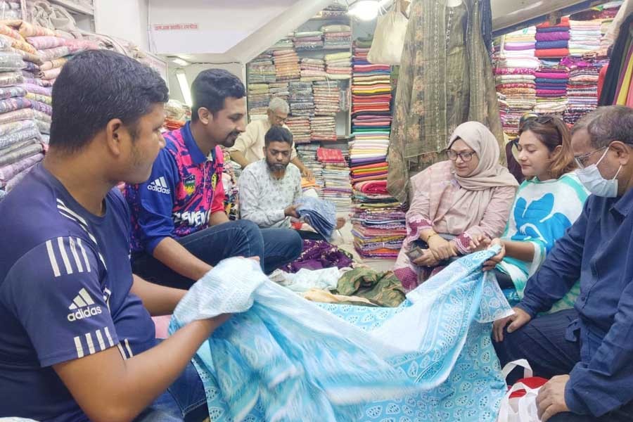 Customers and shopkeepers remain busy at a clothing store in Saheb Bazar Kapor Patti area of Rajshahi city as Eid shopping has started gathering pace- FE Photo