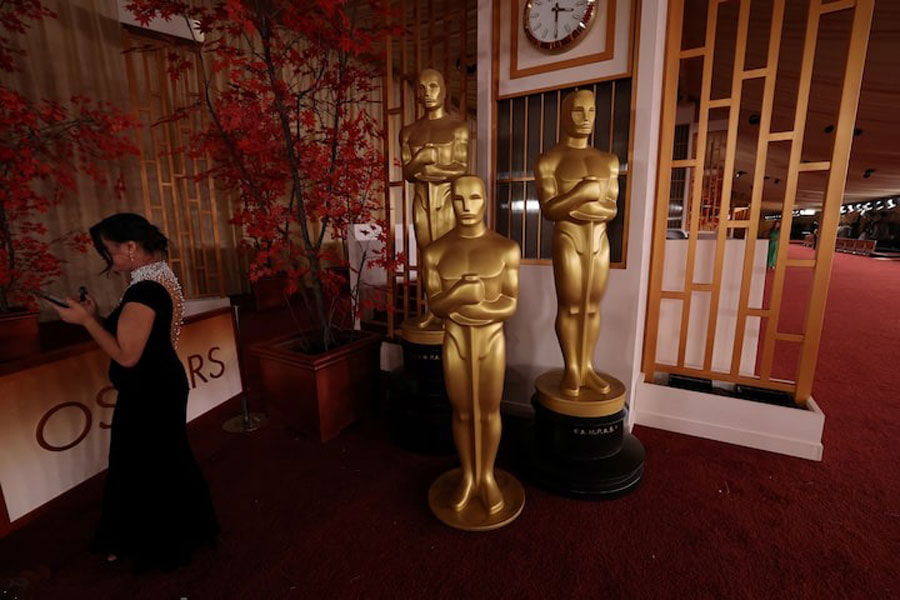 A person uses a mobile phone next to Oscar statues on the red carpet the night prior to the 98th Academy Awards in Los Angeles, California, US, March 14, 2026.