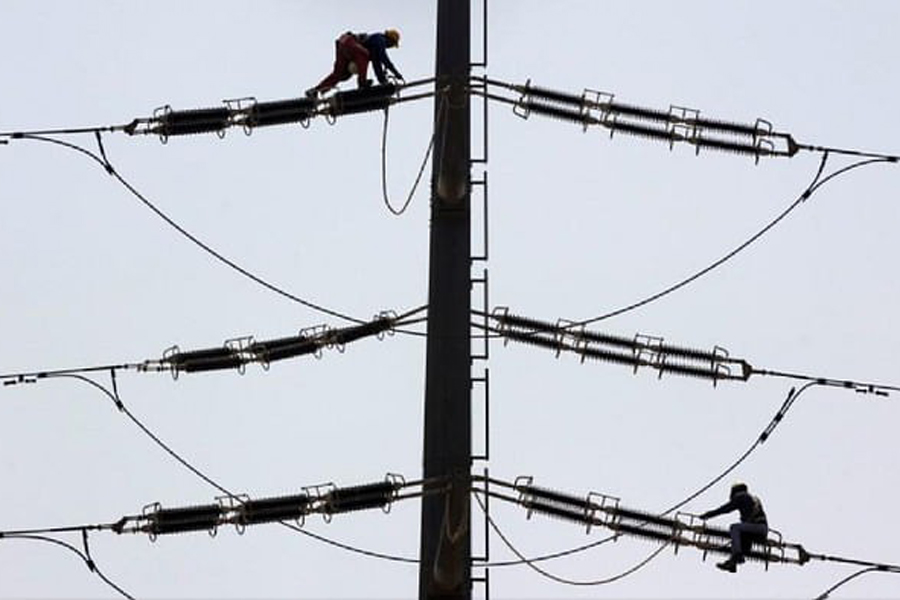 Employees of K-Electric fix cables on a power transmission tower in Karachi, Pakistan, Aug 22, 2016.