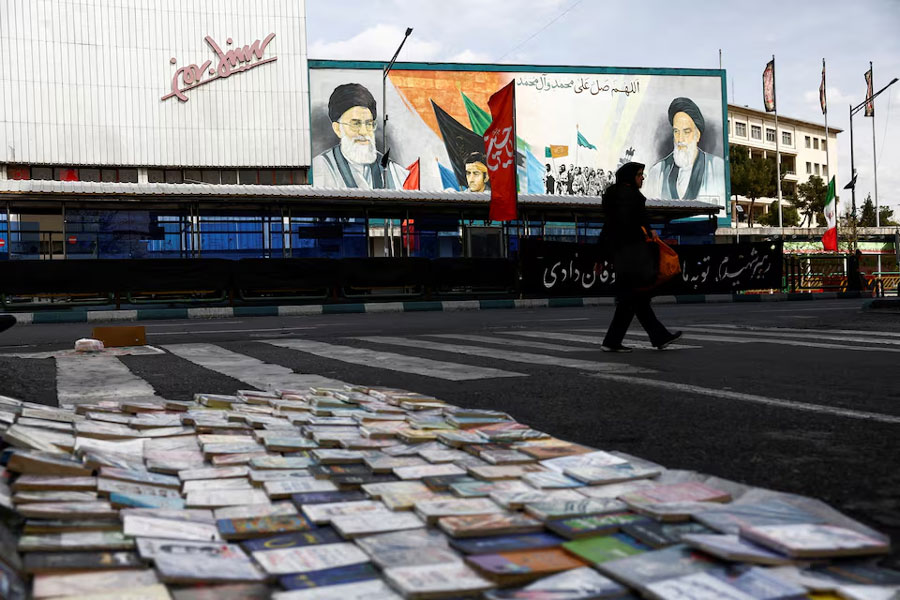 A woman walks next to a mural depicting the late leader of the Islamic Revolution, Ayatollah Ruhollah Khomeini, and the late Supreme Leader of Iran, Ayatollah Ali Khamenei, amid the US-Israeli conflict with Iran, in Tehran, Iran, March 22, 2026.