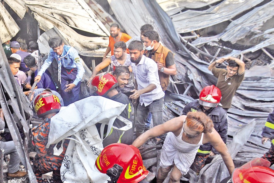 Firefighters and locals recover bodies from the debris after a blaze at an illegal gas lighter factory in Keraniganj's Kadamtali area on Saturday. — Focus Bangla