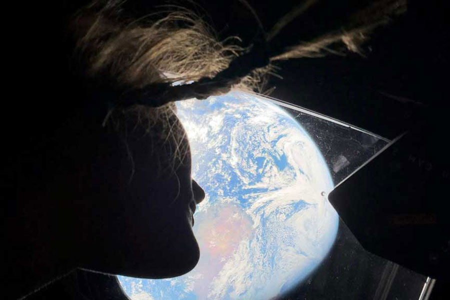 NASA astronaut and Artemis II mission specialist Christina Koch peers out of one of the Orion spacecraft's main cabin windows, looking back at Earth, as the crew travels towards the Moon Apr 2, 2024.