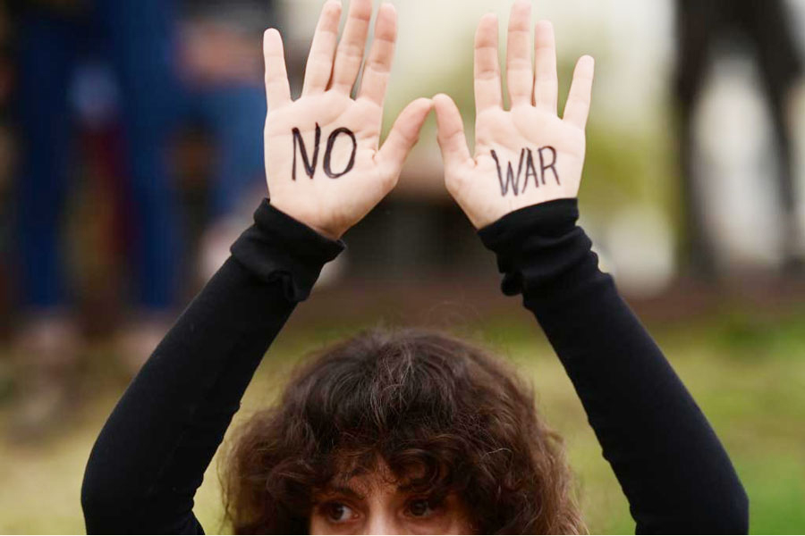 A demonstrator raises hands painted with "No War" slogan during a rally to protest against U.S.-Israeli attacks on Iran and demand an end to all acts of war, in Tel Aviv, Israel, March 14, 2026.