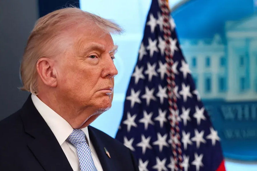 A headshot-style crop shows Trump looking pensively to the right of frame against a backdrop of the stars of the American flag and a plaque picturing the White House, while speaking during a press conference in Washington DC on Monday.