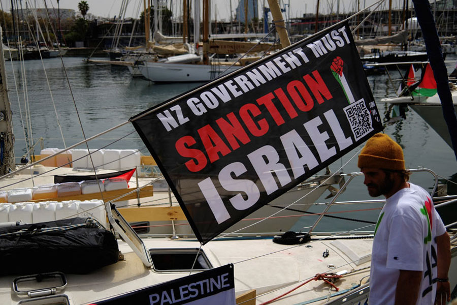 A banner with a message calling for the New Zealand government to sanction Israel hangs on a boat of a humanitarian flotilla preparing to depart for Gaza, in Barcelona, Spain, Apr 11, 2026.