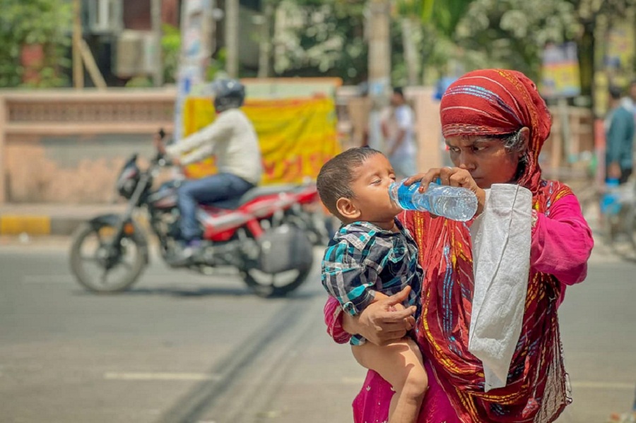 Mother giving little son water on the street.