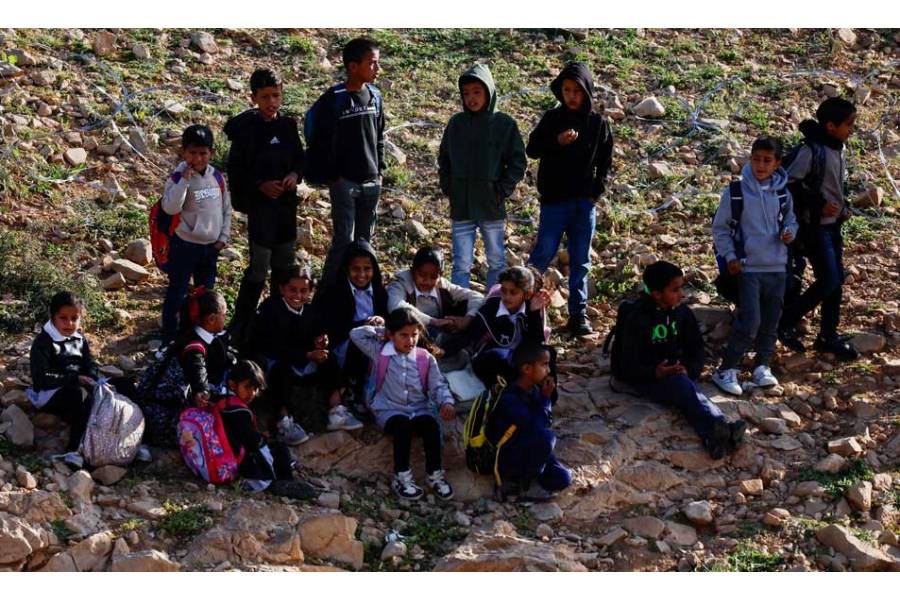 Palestinian school children gather by a barbed wire fence installed by Israeli settlers, which blocked their access to the school in Umm al-Khair village in Masafer Yatta, in the Israeli-occupied West Bank, Apr 14, 2026.