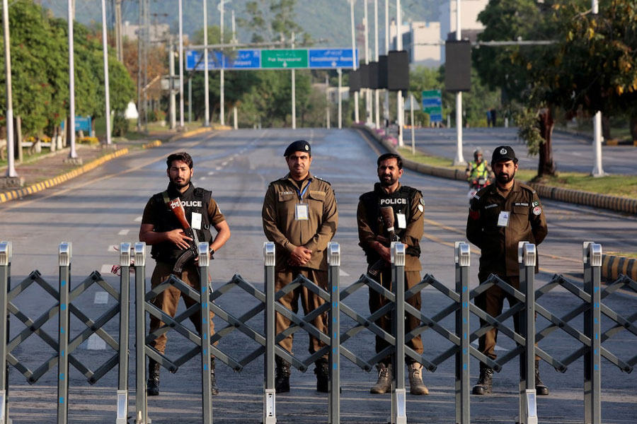 Police officers stand guard behind a barricade near Serena Hotel in Islamabad, Pakistan, April 25, 2026.
