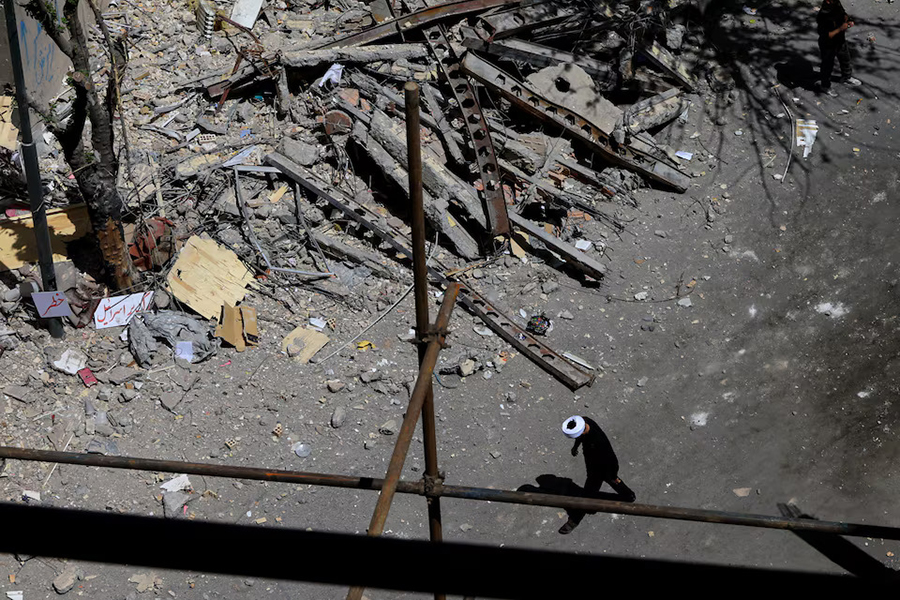 A cleric walks near a residential building damaged by a strike on March 4, in Tehran, Iran on April 14, 2026 — Reuters/File