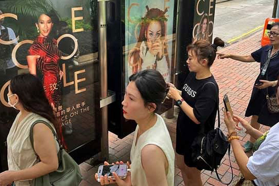 People take pictures of images in tribute to late singer Coco Lee, at a bus stop near the Hong Kong Funeral Home in Hong Kong, China Jul 31, 2023.