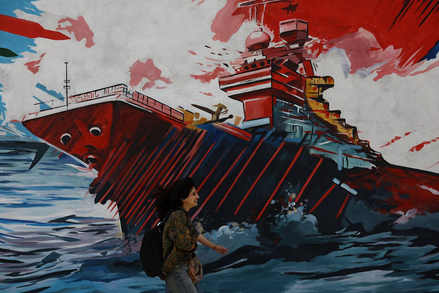 An Iranian woman walks next to a mural on a street in Tehran, Iran, May 6, 2026.