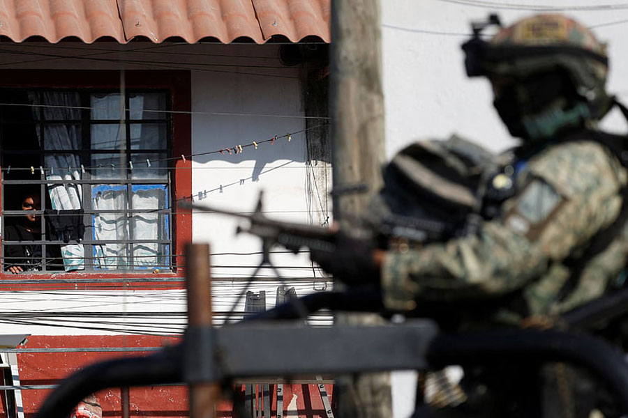 A person watches from their window as soldiers guard a street days after a series of blockades and attacks by organized crime following a military operation in which cartel boss Nemesio Oseguera, "El Mencho," was killed, on the outskirts of Puerto Vallarta, in Ixtapa, Mexico, Feb 24, 2026.