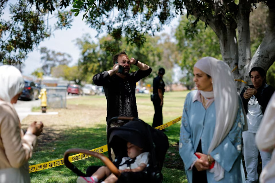 Members of the Muslim community use their phones at the scene of a reported active shooter situation at the Islamic Center, with yellow tape placed behind them to cordon the area, in San Diego, California, US, on May 18, 2026 — Reuters photo