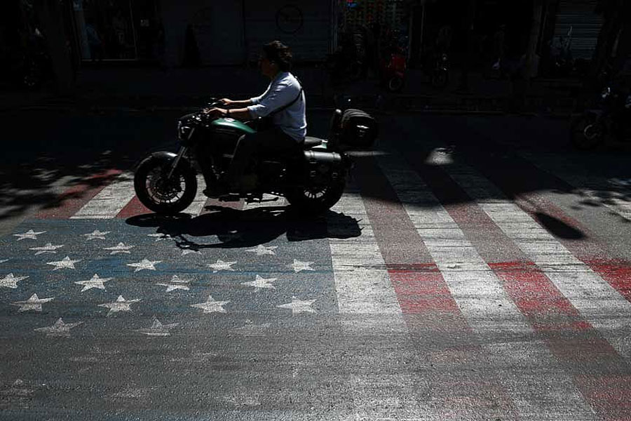 A person rides a motorcycle over a US flag painted on a street, in Tehran, Iran, May 12, 2026.