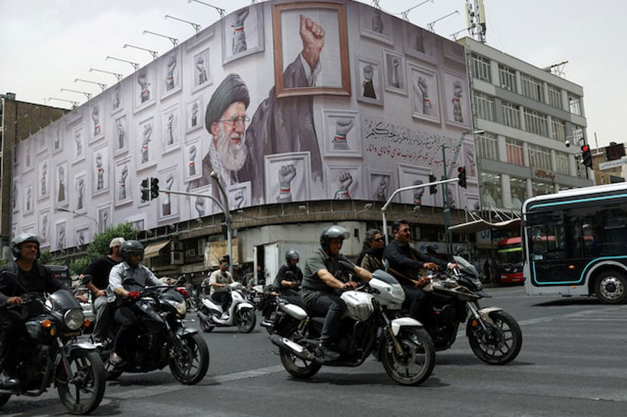 People ride motorcycles near a billboard with an image of the late Iranian Supreme Leader Ayatollah Ali Khamenei, in Tehran, Iran, May 19, 2026.